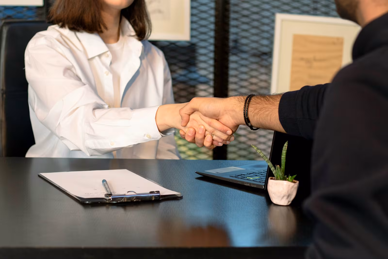 An operator and a decision-maker shaking hands across a desk